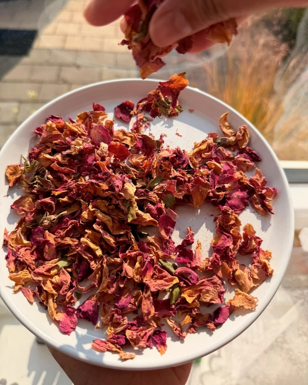 Dried rose petals and spices being prepared by hand