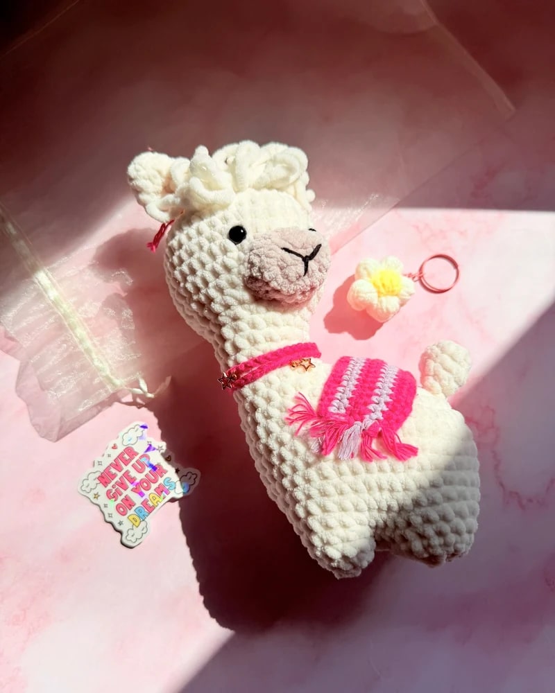 Handmade white llama mascot wearing a pink Joyful Bakehouse apron